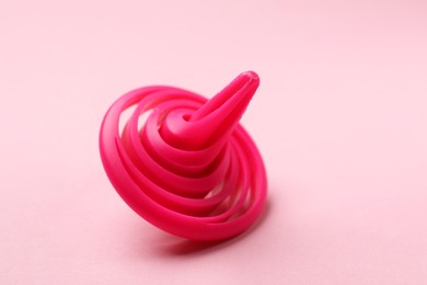 Photo of One spinning top on pink background, closeup. Space for text