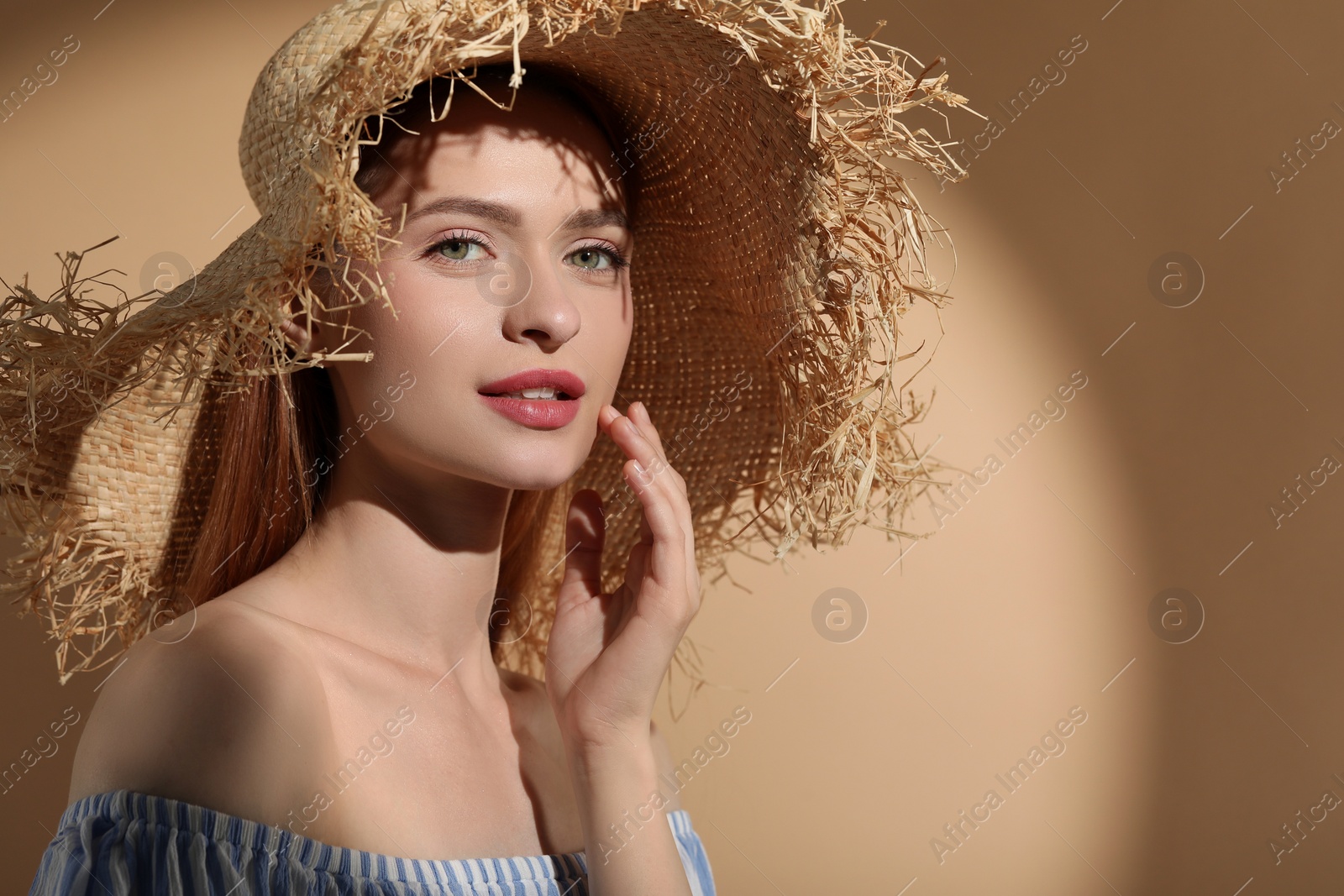 Photo of Beautiful young woman in sunlight on beige background, space for text