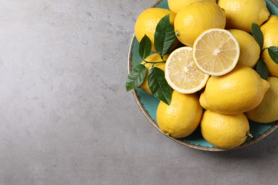 Photo of Fresh lemons and green leaves on grey table, top view. Space for text