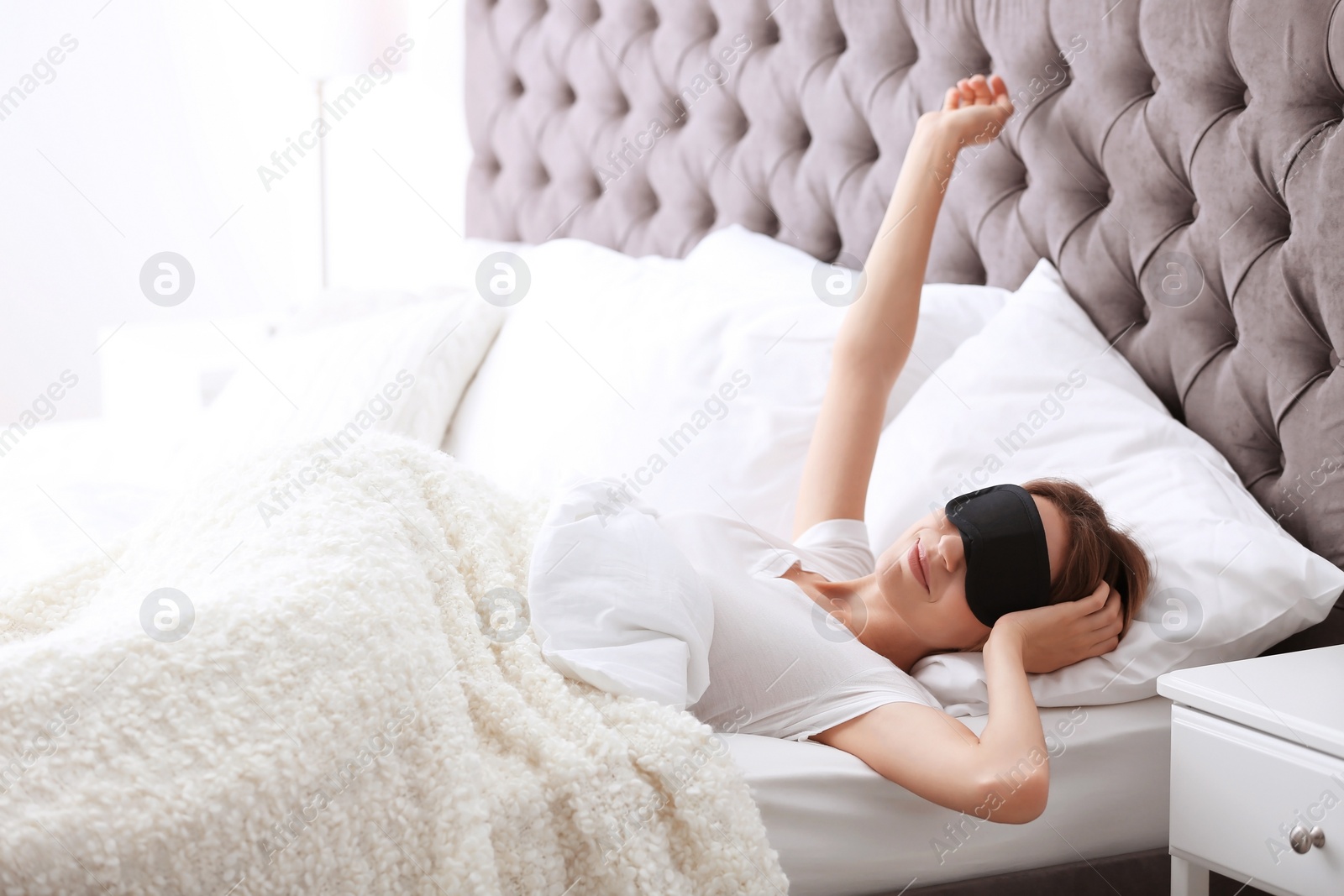 Photo of Young beautiful woman with sleeping mask waking up in morning at home