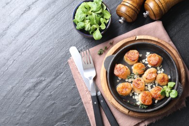 Delicious fried scallops in dish served on dark gray textured table, flat lay. Space for text