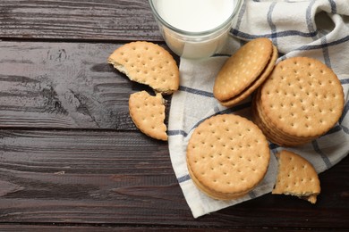 Photo of Tasty sandwich cookies and glass of milk on wooden table, flat lay. Space for text