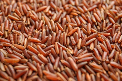 Photo of Pile of uncooked red rice as background, closeup