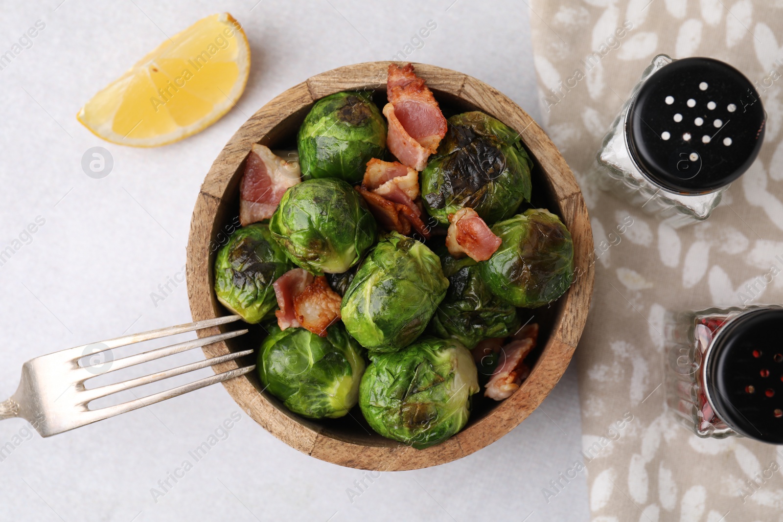 Photo of Delicious roasted Brussels sprouts and bacon served on light table, top view