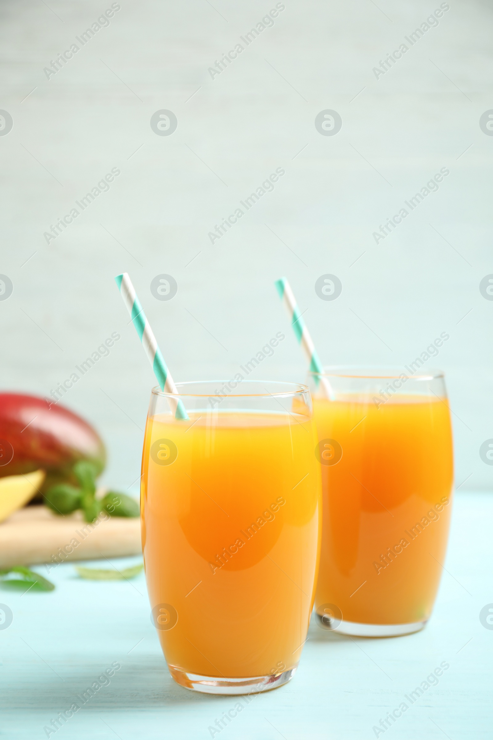 Photo of Fresh delicious mango drink on light blue wooden table