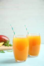 Fresh delicious mango drink on light blue wooden table