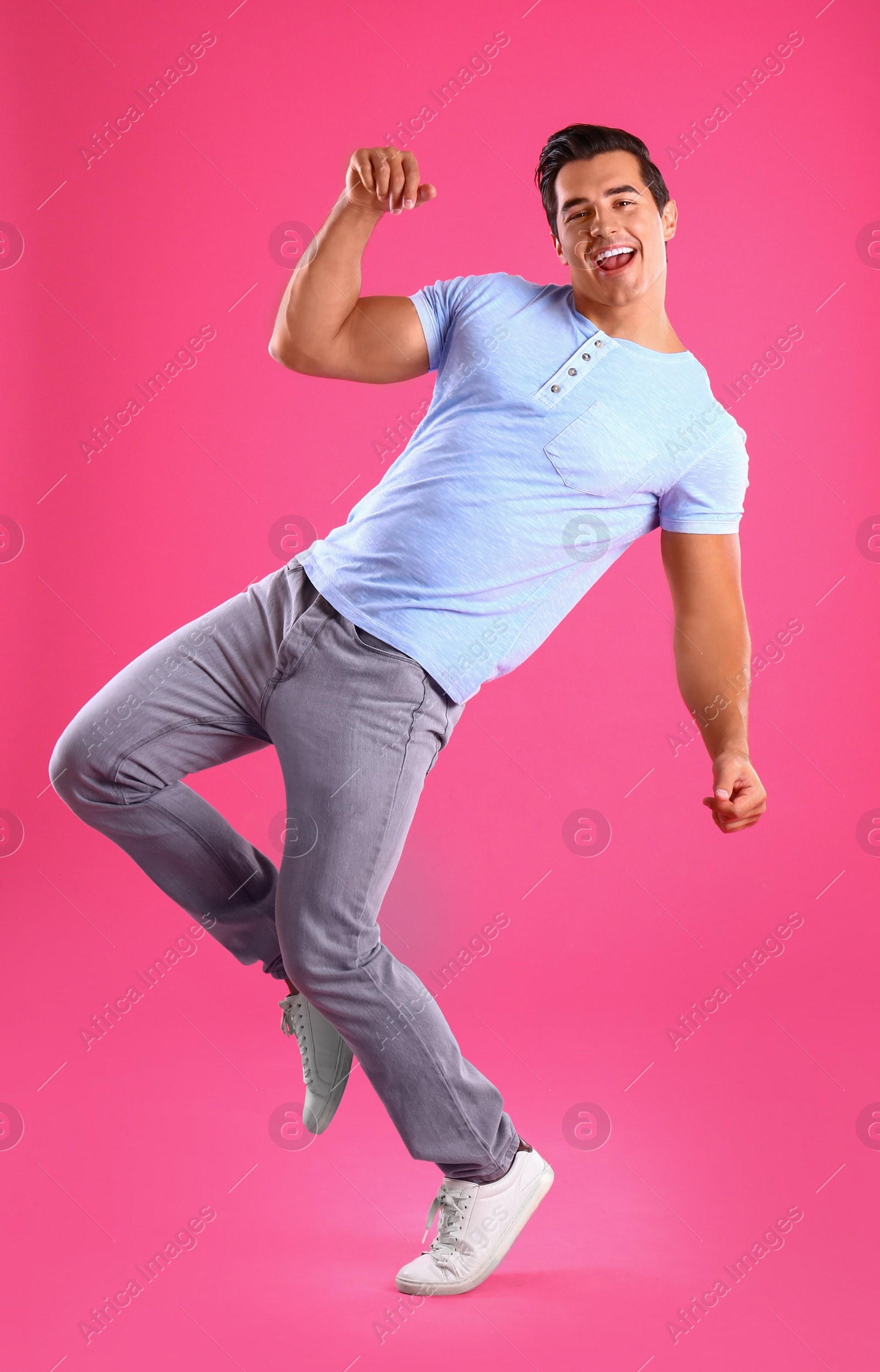 Photo of Handsome young man dancing on pink background