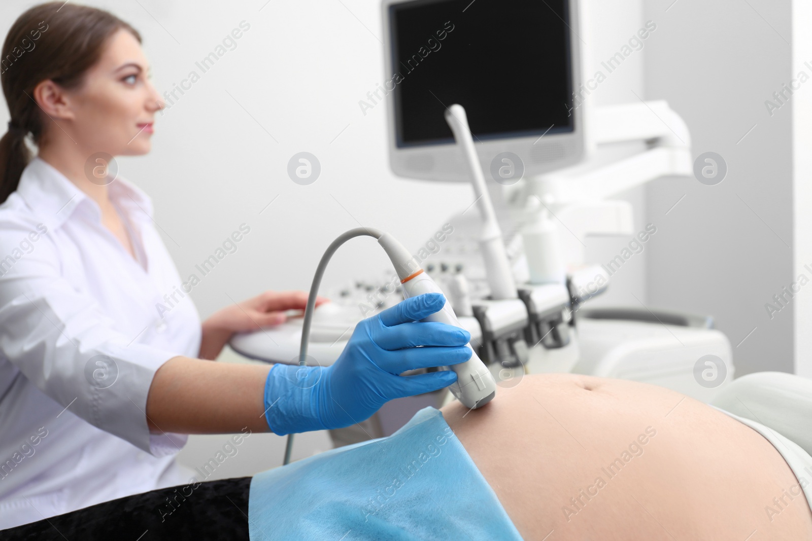 Photo of Young pregnant woman undergoing ultrasound scan in clinic