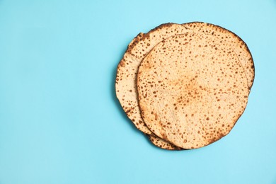 Photo of Tasty matzos on light blue background, flat lay with space for text. Passover (Pesach) celebration
