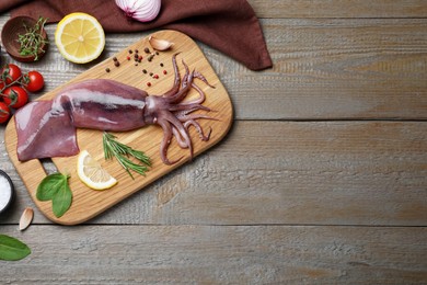 Flat lay composition with fresh raw squid and garnish ingredients on wooden table. Space for text
