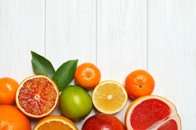 Photo of Flat lay composition with different citrus fruits and space for text on white wooden background