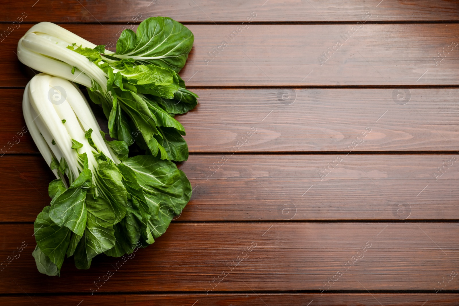 Photo of Fresh green pak choy cabbages on wooden table, flat lay. Space for text