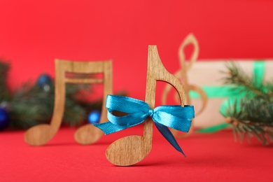 Wooden music note with blue bow on red background, closeup. Christmas celebration