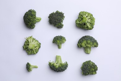 Photo of Many fresh green broccoli pieces on white background, flat lay