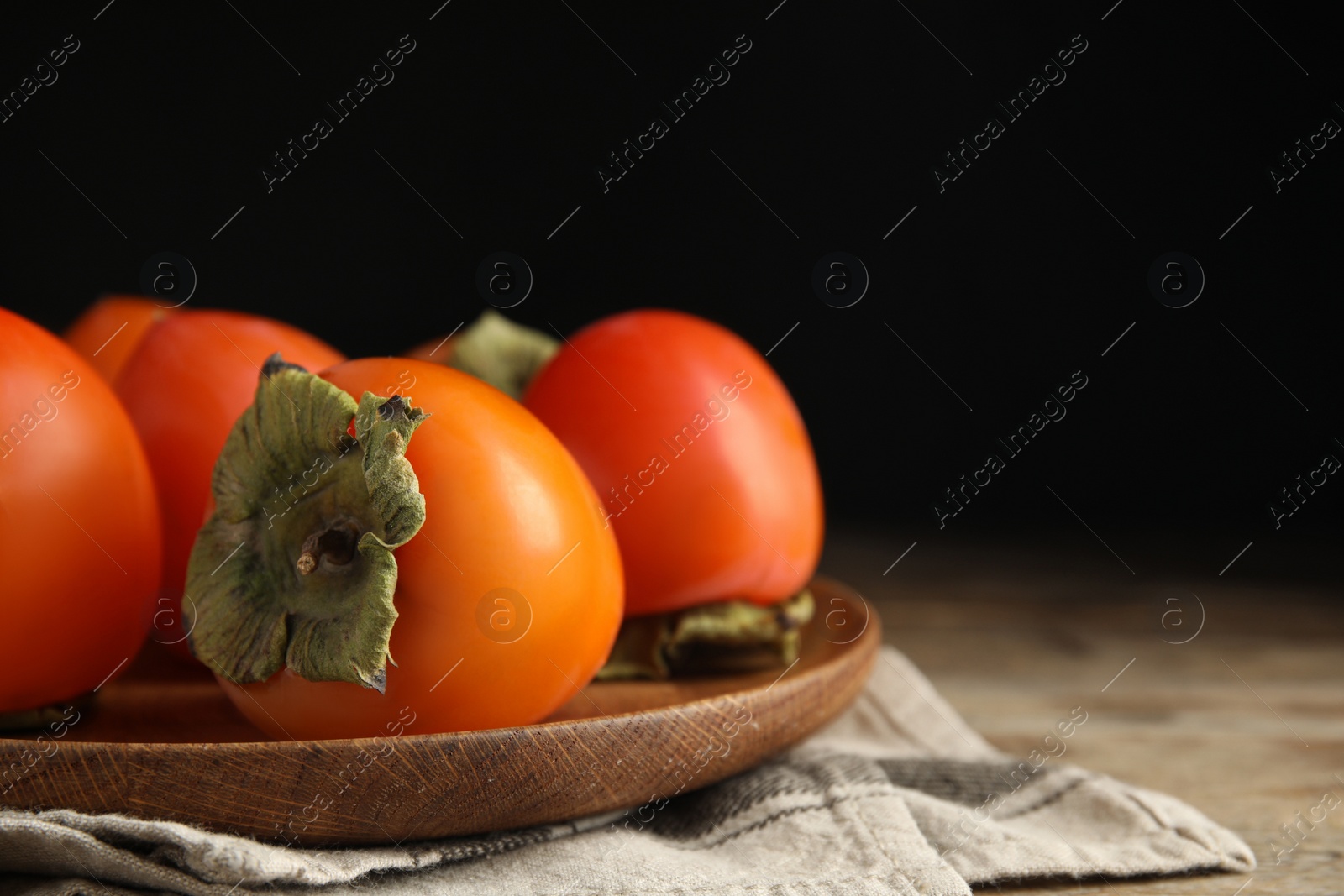 Photo of Tasty fresh ripe persimmons on table, closeup. Space for text