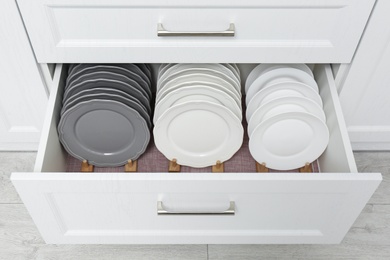 Photo of Open drawer with clean plates indoors. Order in kitchen