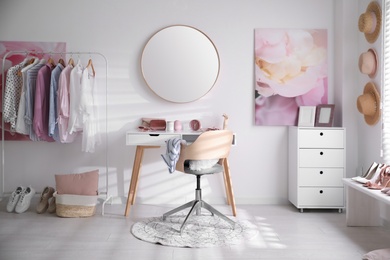 Dressing room interior with stylish makeup table, clothes and accessories