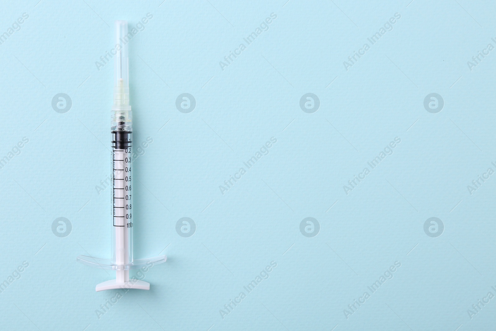 Photo of Cosmetology. Medical syringe on light blue background, top view. Space for text