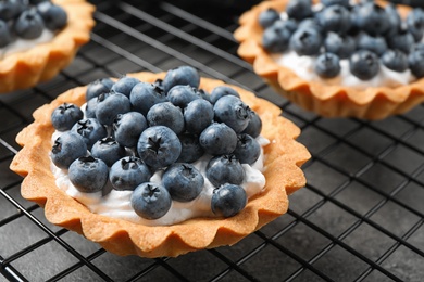 Photo of Delicious sweet pastry with berries on cooling rack, closeup