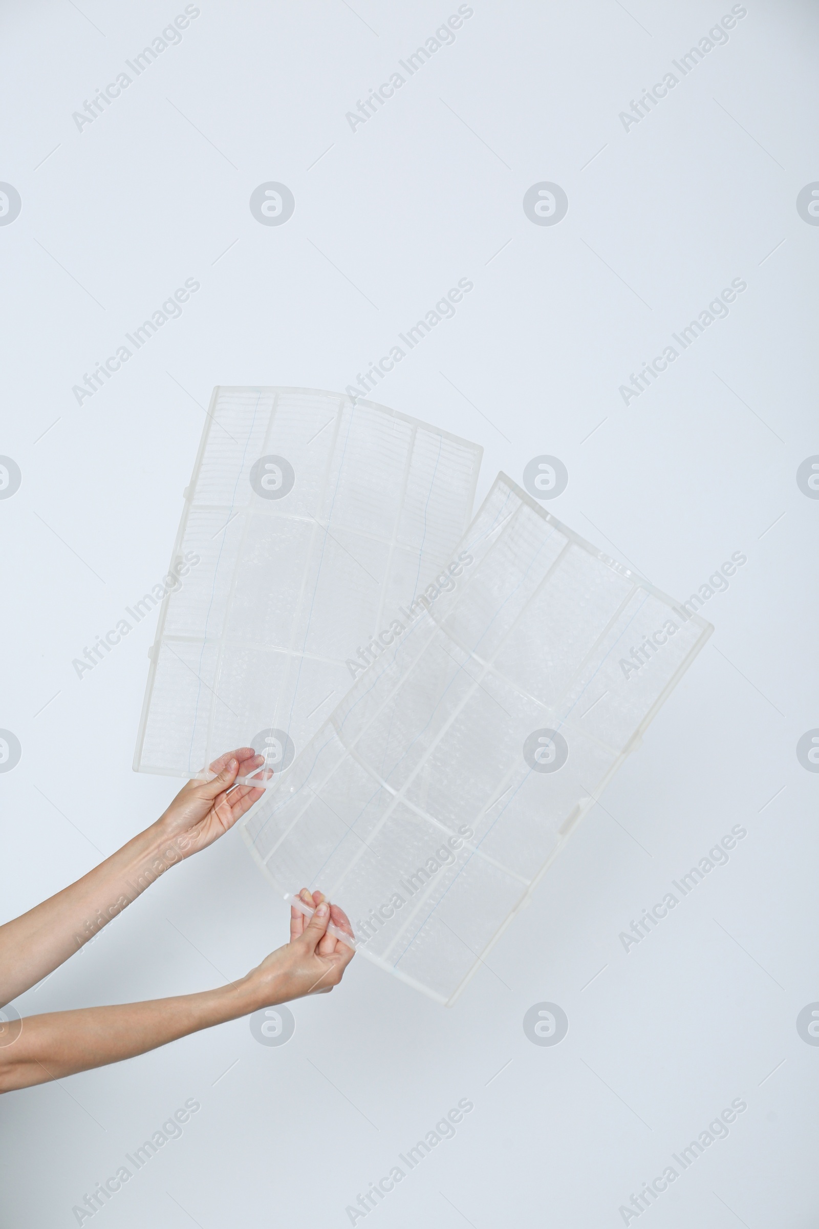 Photo of Woman holding air conditioner filters near white wall, closeup