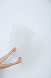 Woman holding air conditioner filters near white wall, closeup