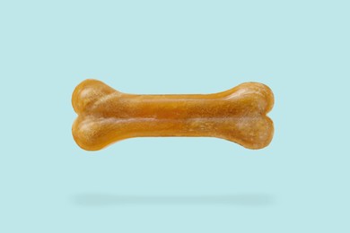 Image of Bone dog treat in air on light blue background