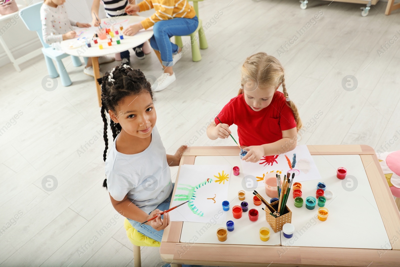 Photo of Cute little children painting at lesson indoors