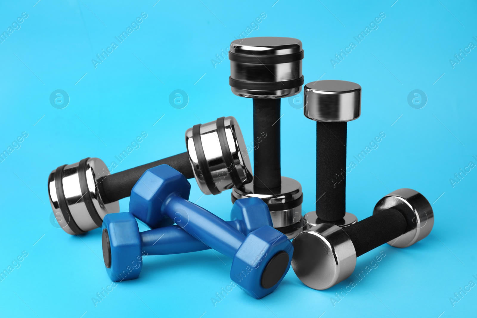 Photo of Many different stylish dumbbells on light blue background