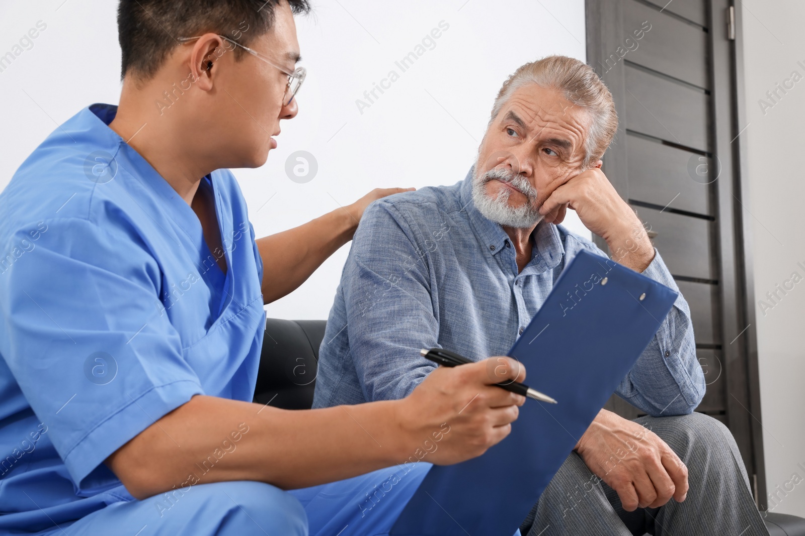 Photo of Doctor with clipboard consulting senior patient in clinic