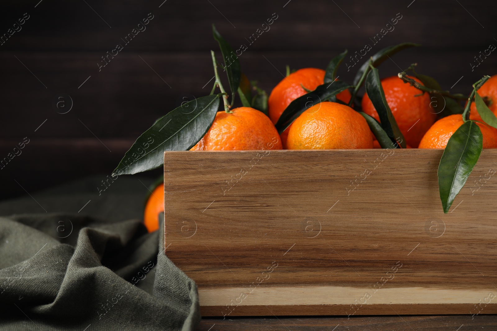 Photo of Wooden crate with fresh ripe tangerines and leaves on table