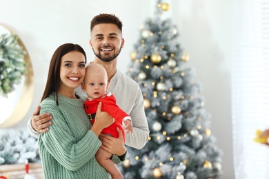 Photo of Happy family with cute baby at home, space for text. Christmas celebration