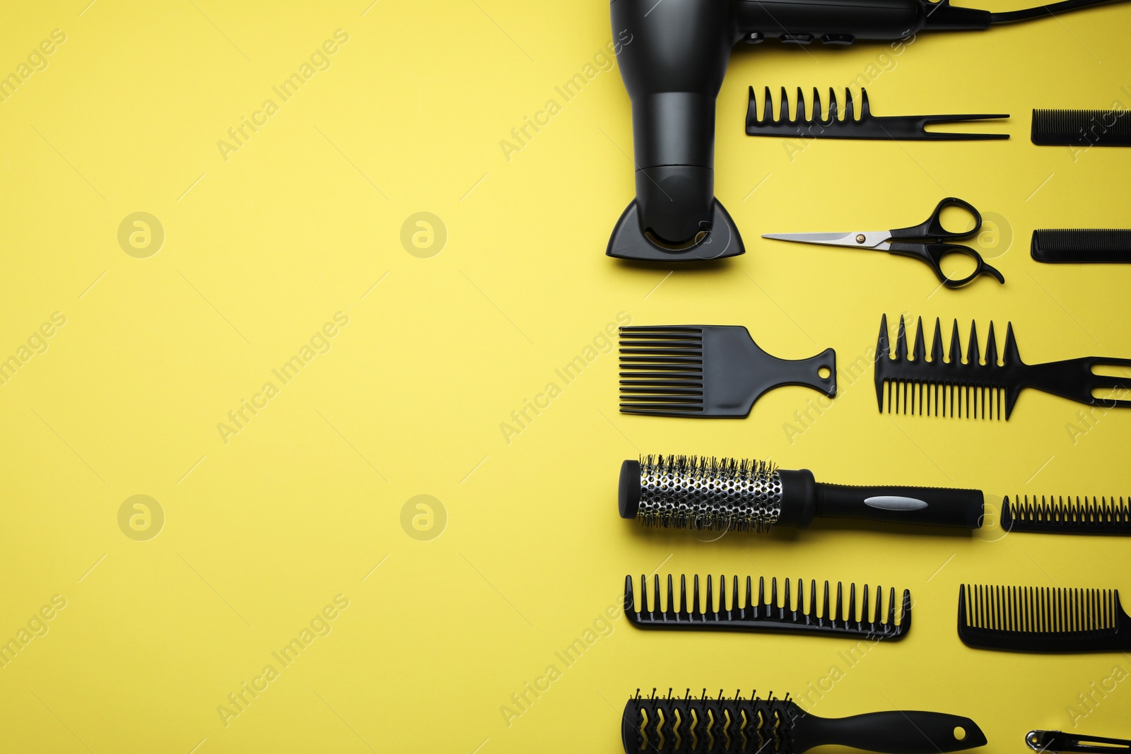 Photo of Flat lay composition of professional hairdresser tools on yellow background, space for text