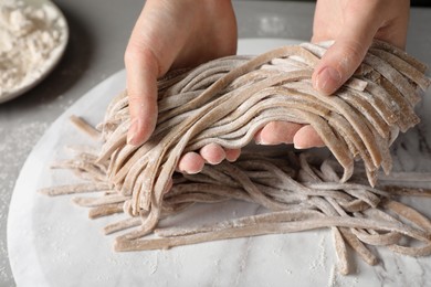 Photo of Woman making soba (buckwheat noodles) at table, closeup