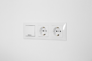 Light switch and power sockets on white wall indoors