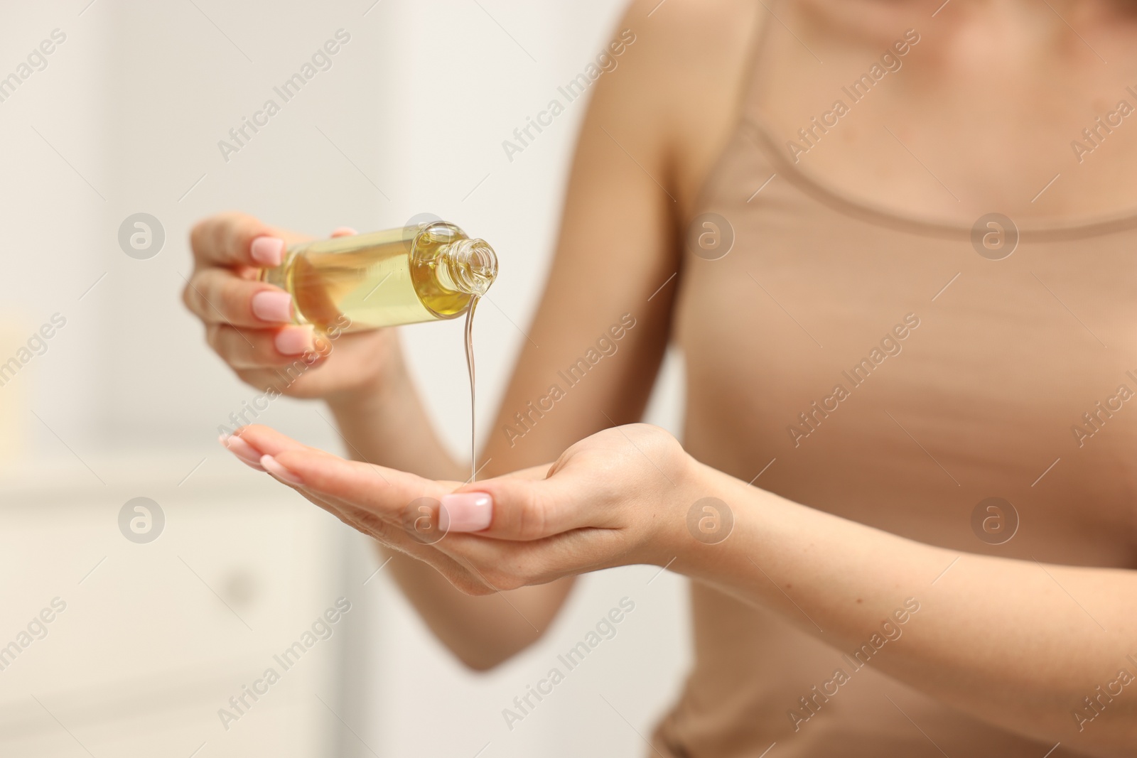 Photo of Aromatherapy. Woman with bottle of essential oil on light background, closeup