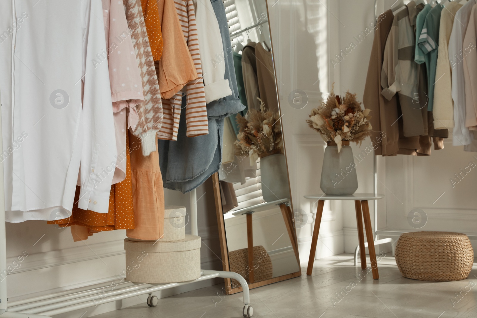 Photo of Modern dressing room interior with stylish clothes and beautiful dry flowers