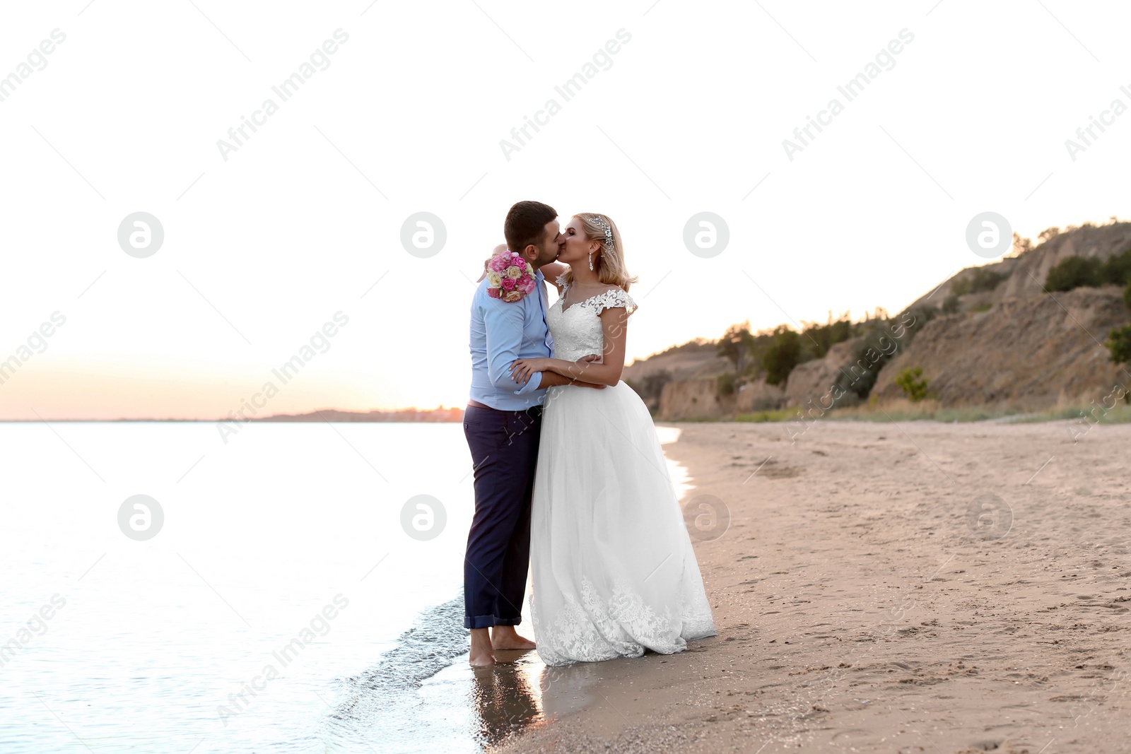 Photo of Wedding couple. Bride and groom kissing on beach