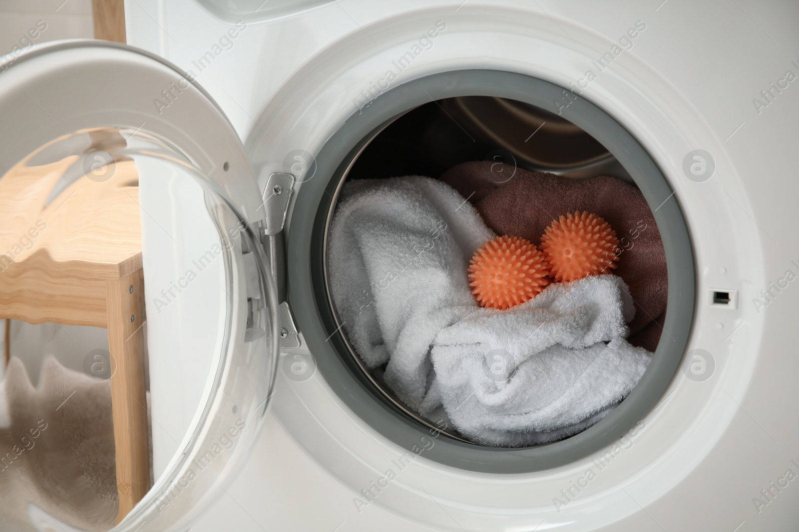 Photo of Dryer balls and towels in washing machine, closeup