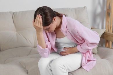 Young woman suffering from cystitis on sofa at home
