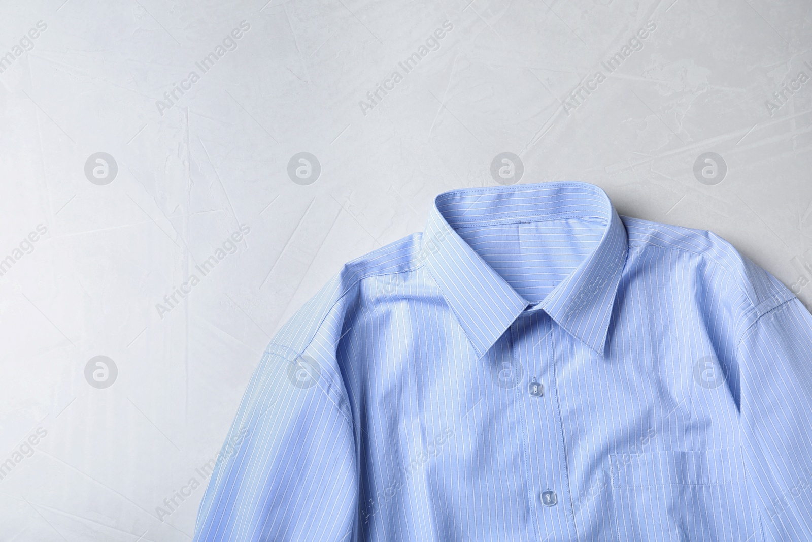 Photo of Stylish light blue shirt on light table, top view with space for text. Dry-cleaning service