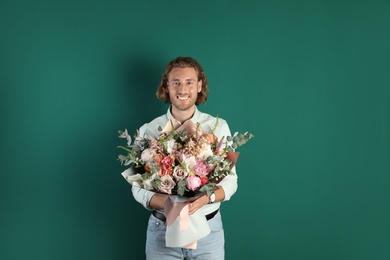 Photo of Young handsome man with beautiful flower bouquet on green background