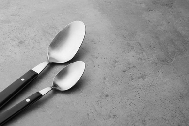 Photo of Clean empty table spoons on grey background, space for text