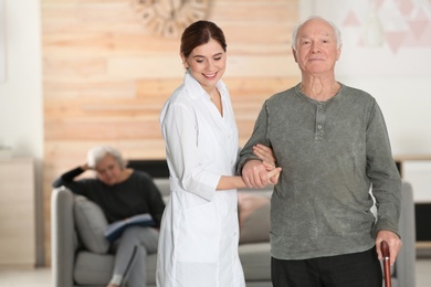 Photo of Elderly man with female caregiver in living room. Space for text
