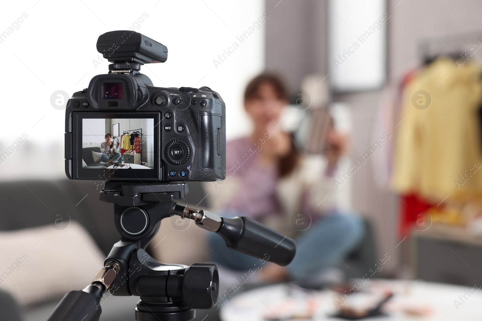 Photo of Beauty blogger recording makeup tutorial at home, focus on camera