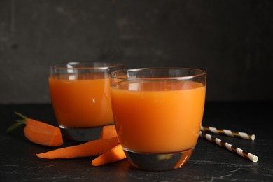 Glasses of freshly made carrot juice on black table