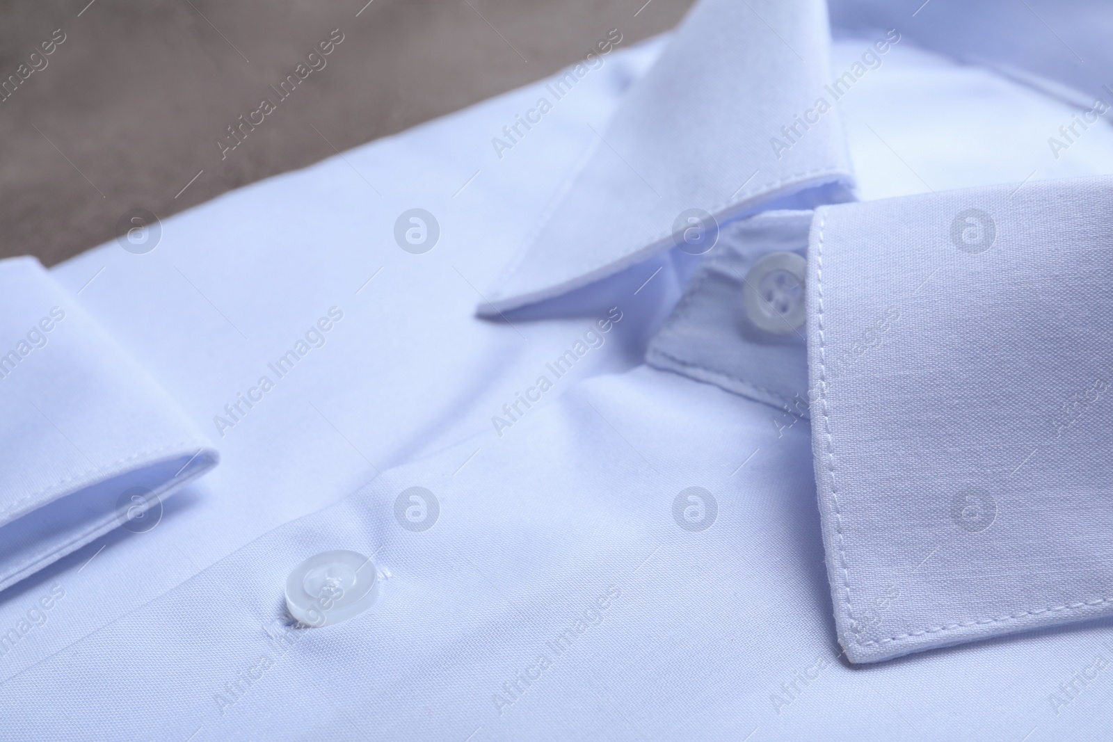 Photo of Stylish white shirt on grey table, closeup. Dry-cleaning service