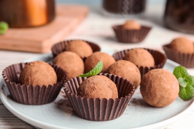 Photo of Plate with chocolate truffles on table, closeup