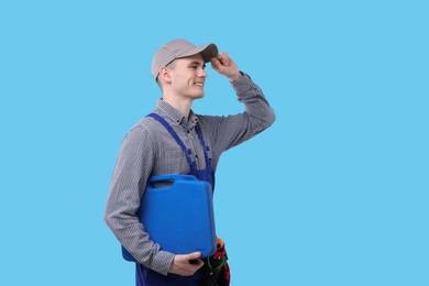 Professional repairman with tool box on light blue background