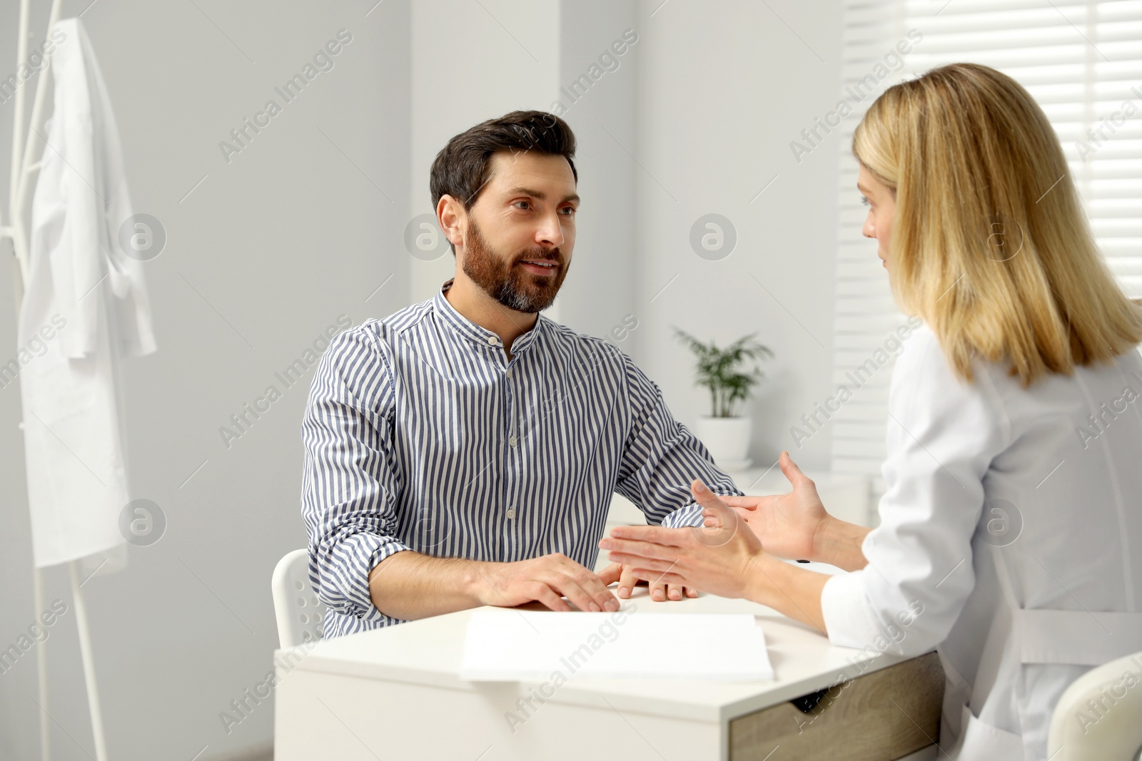 Photo of Doctor consulting patient at white table in clinic