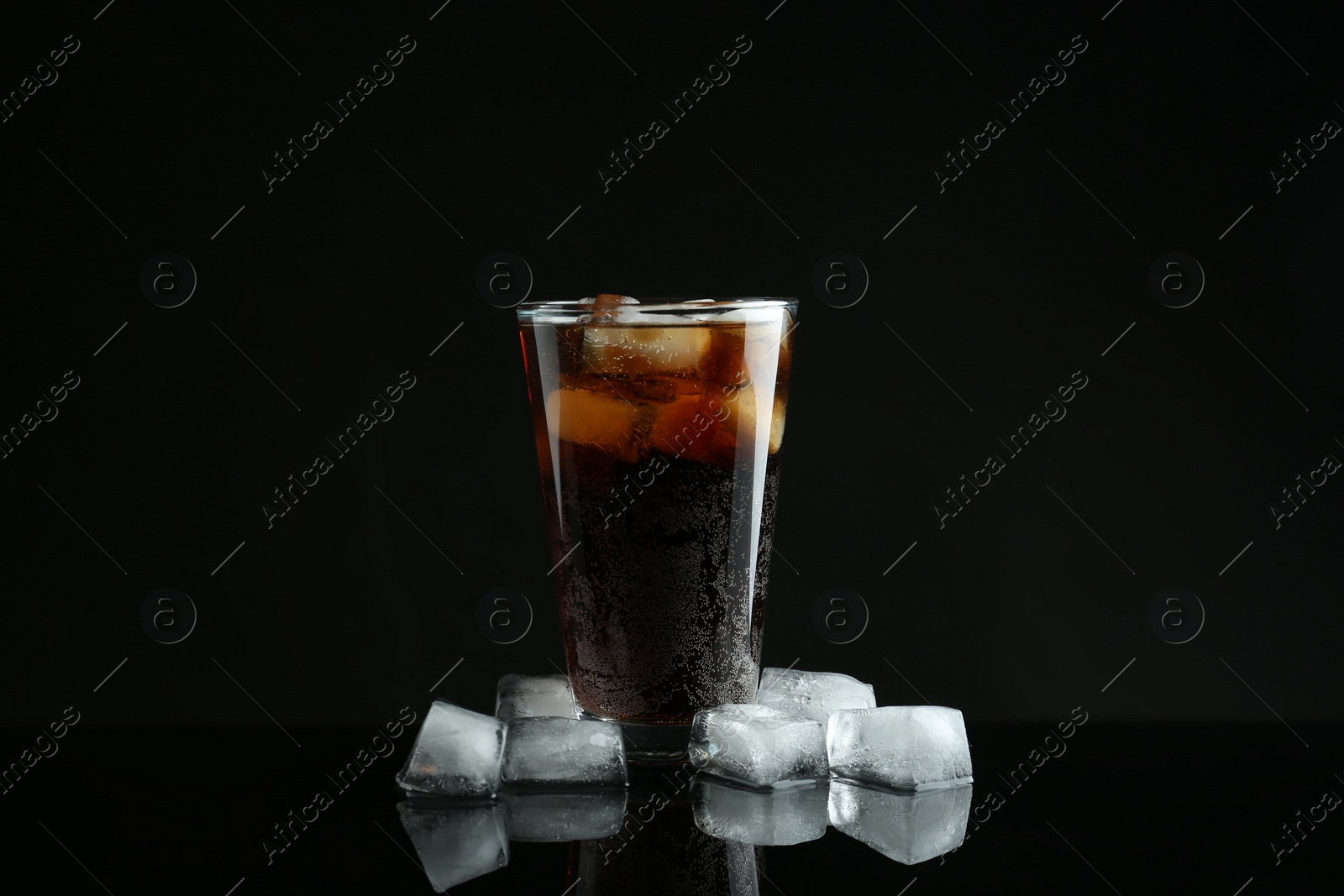 Photo of Glass of refreshing soda water with ice cubes on black background